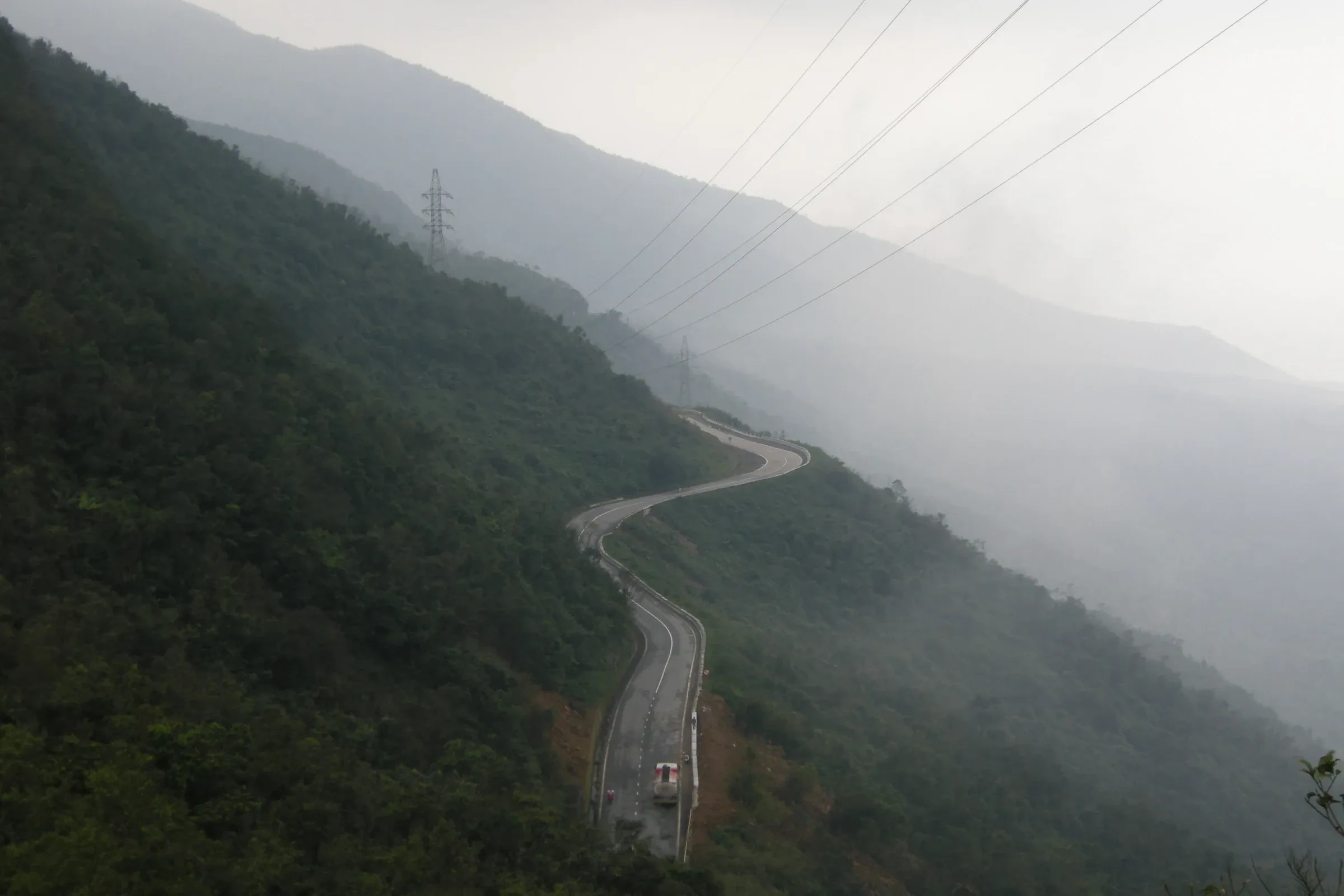 The winding Hai Van Pass road climbing through forested hills above the coast