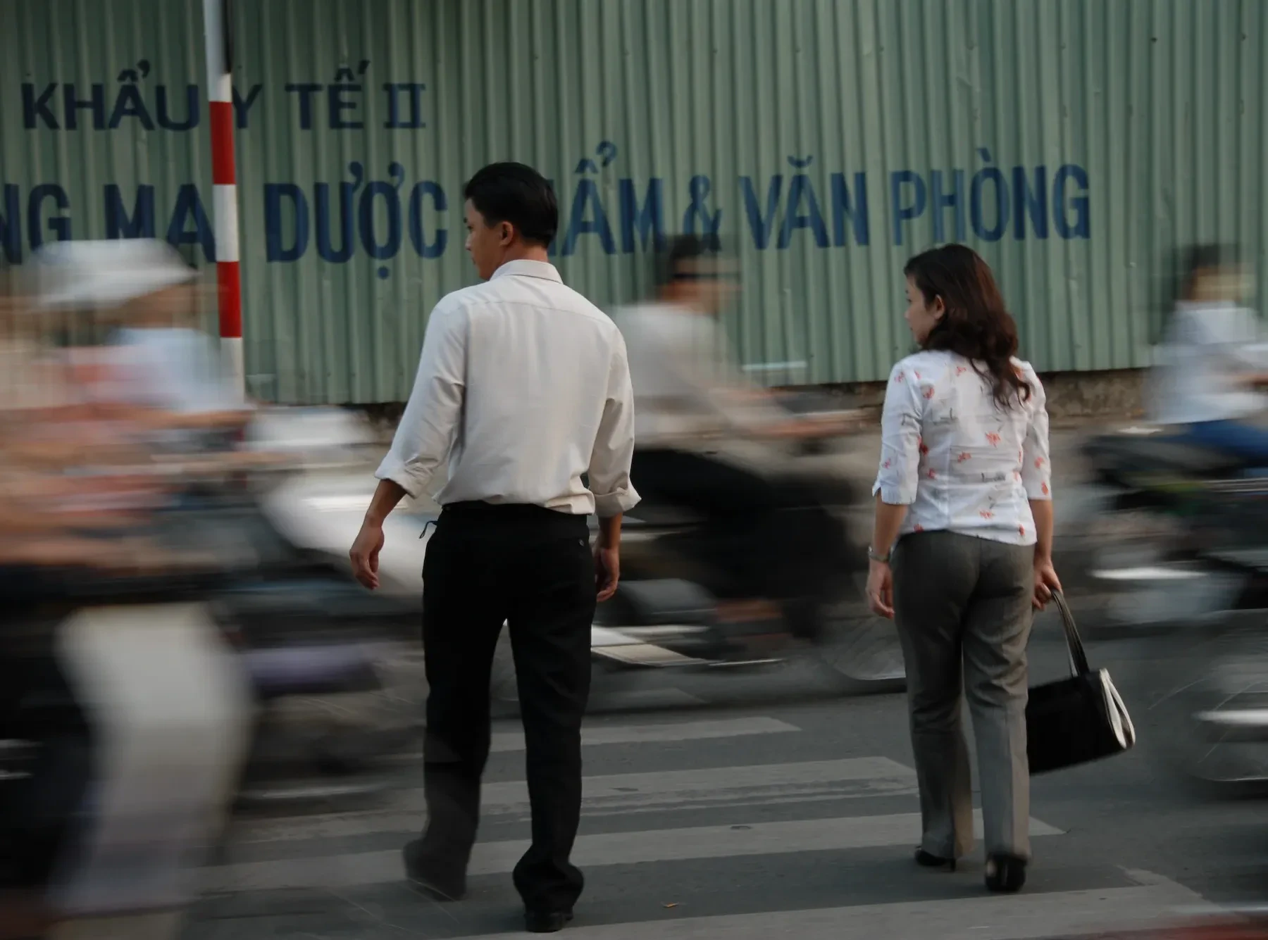 Pedestrians crossing a Saigon street with motorbikes blurring past